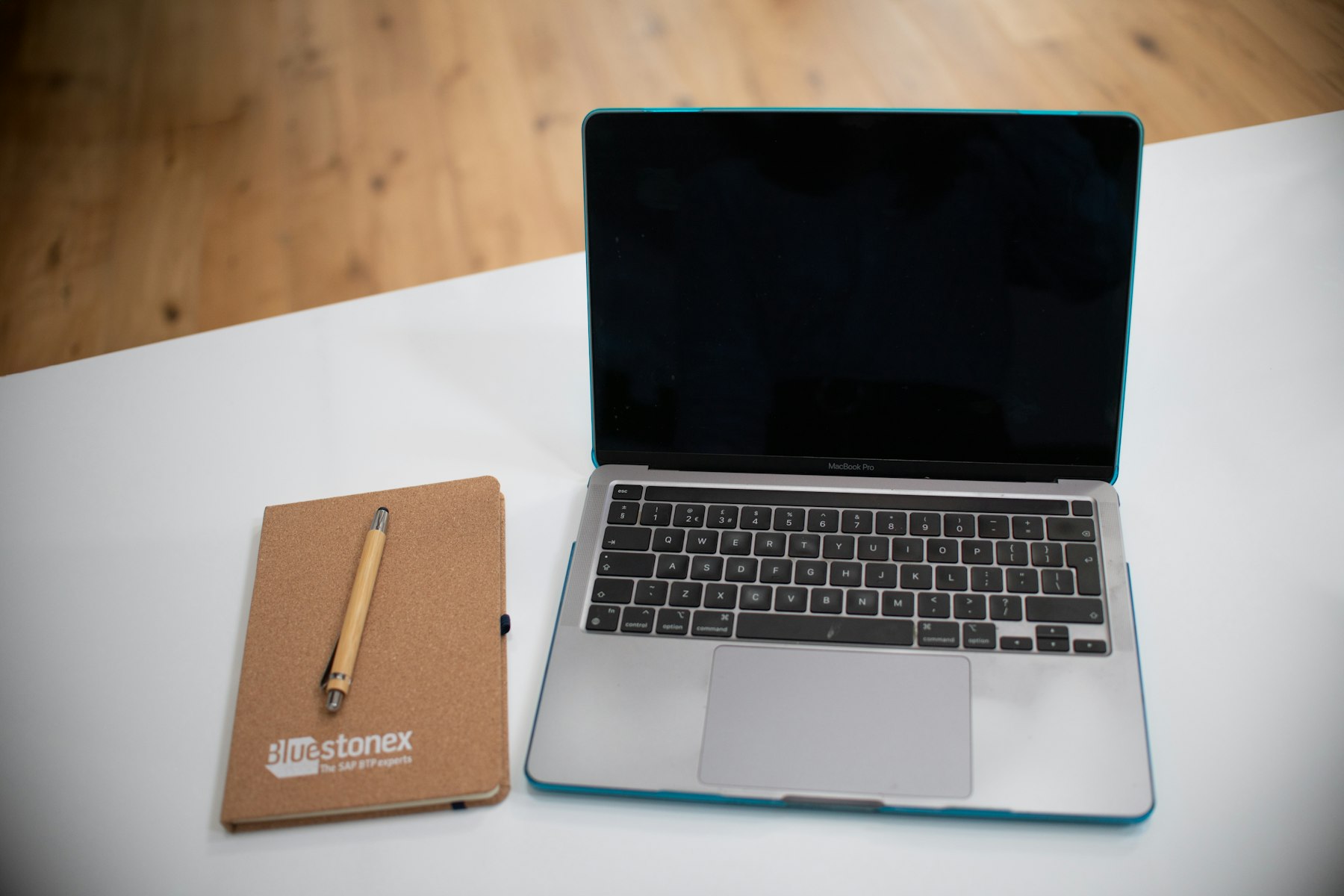 Laptop and notebook with pen on a desk for logo planning.