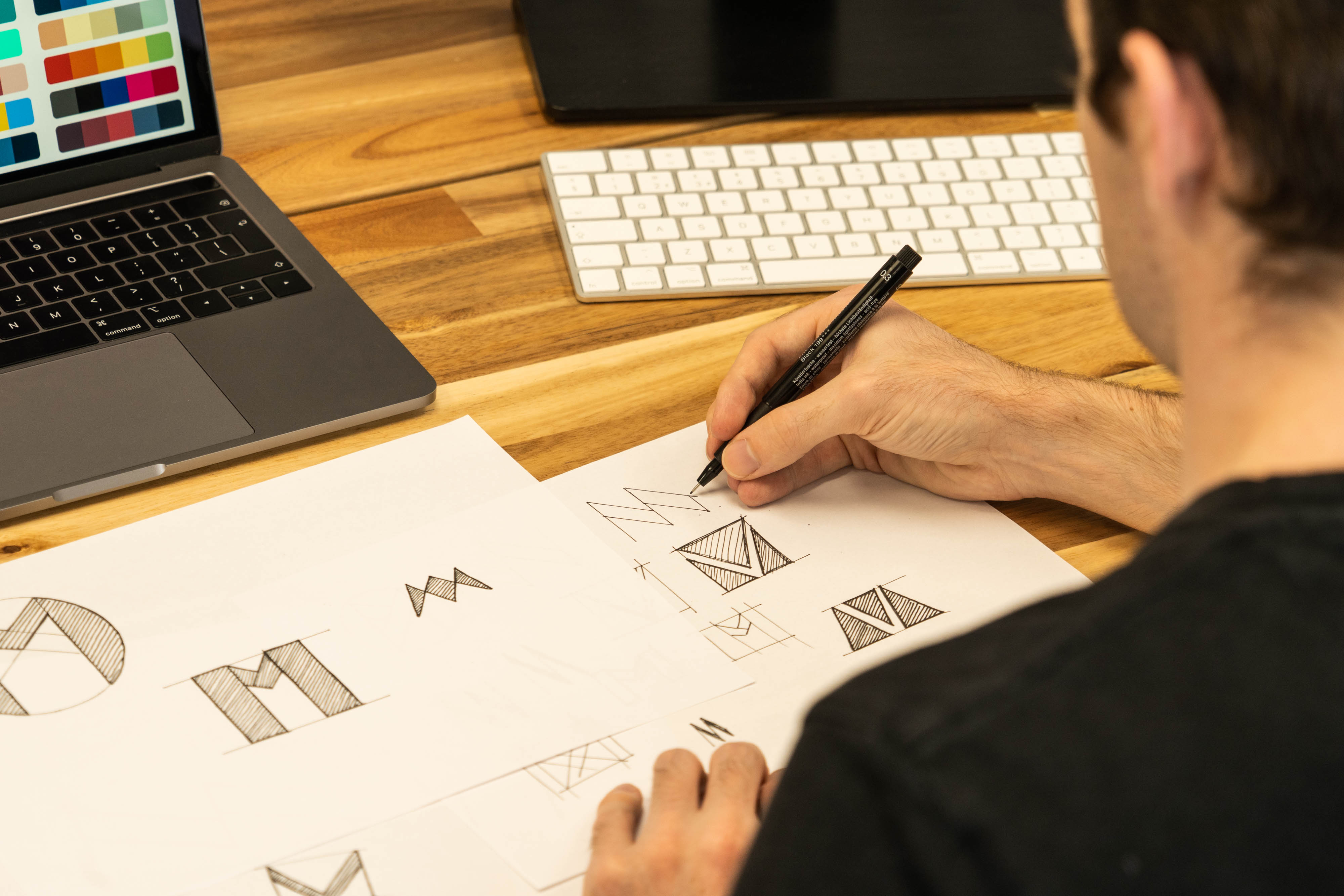 Prepared logo concept sheets, laptop, and color notes laid out for a design submission review.